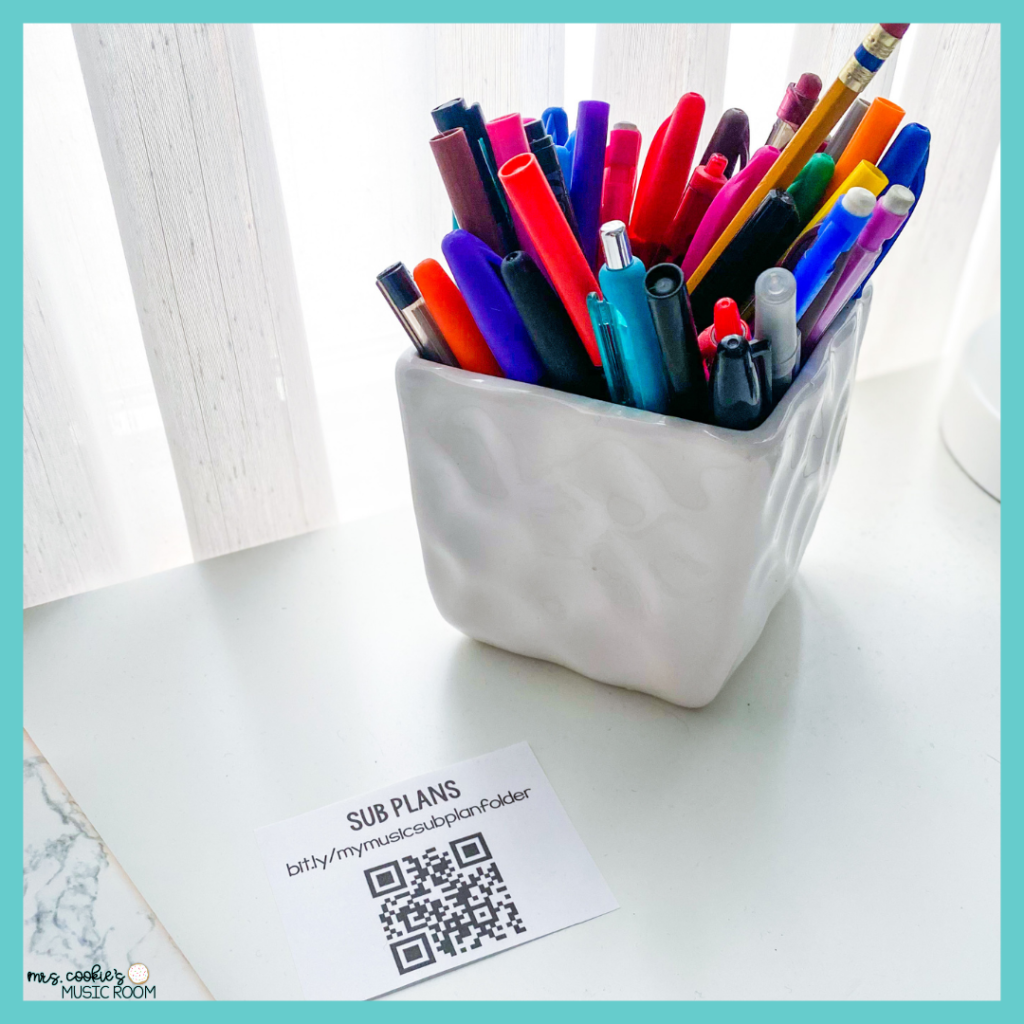 photo of a qr code printed and cut out from a piece of paper, placed on a white desk with a cup of writing utensils next to it